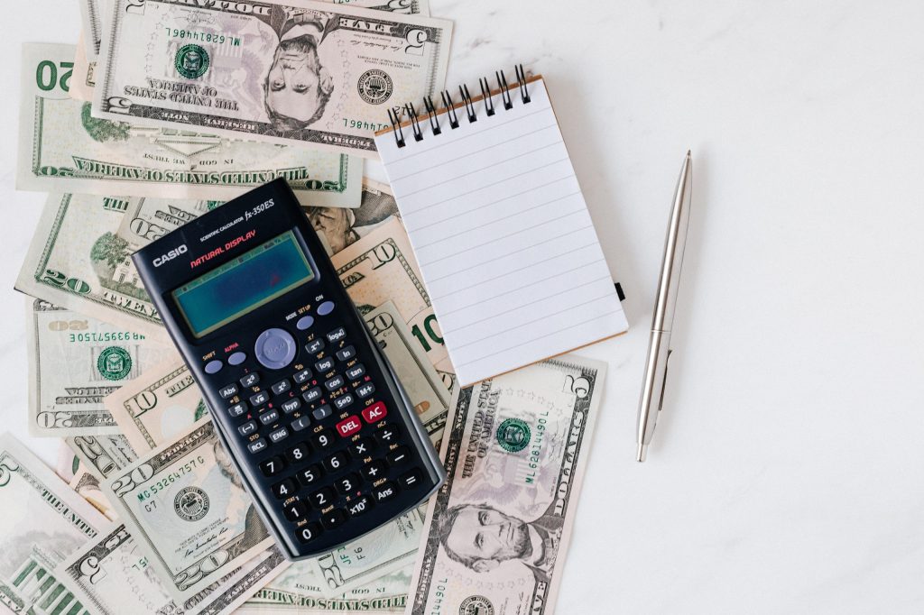 A calculator and money being used to budget expenses to pay off debt